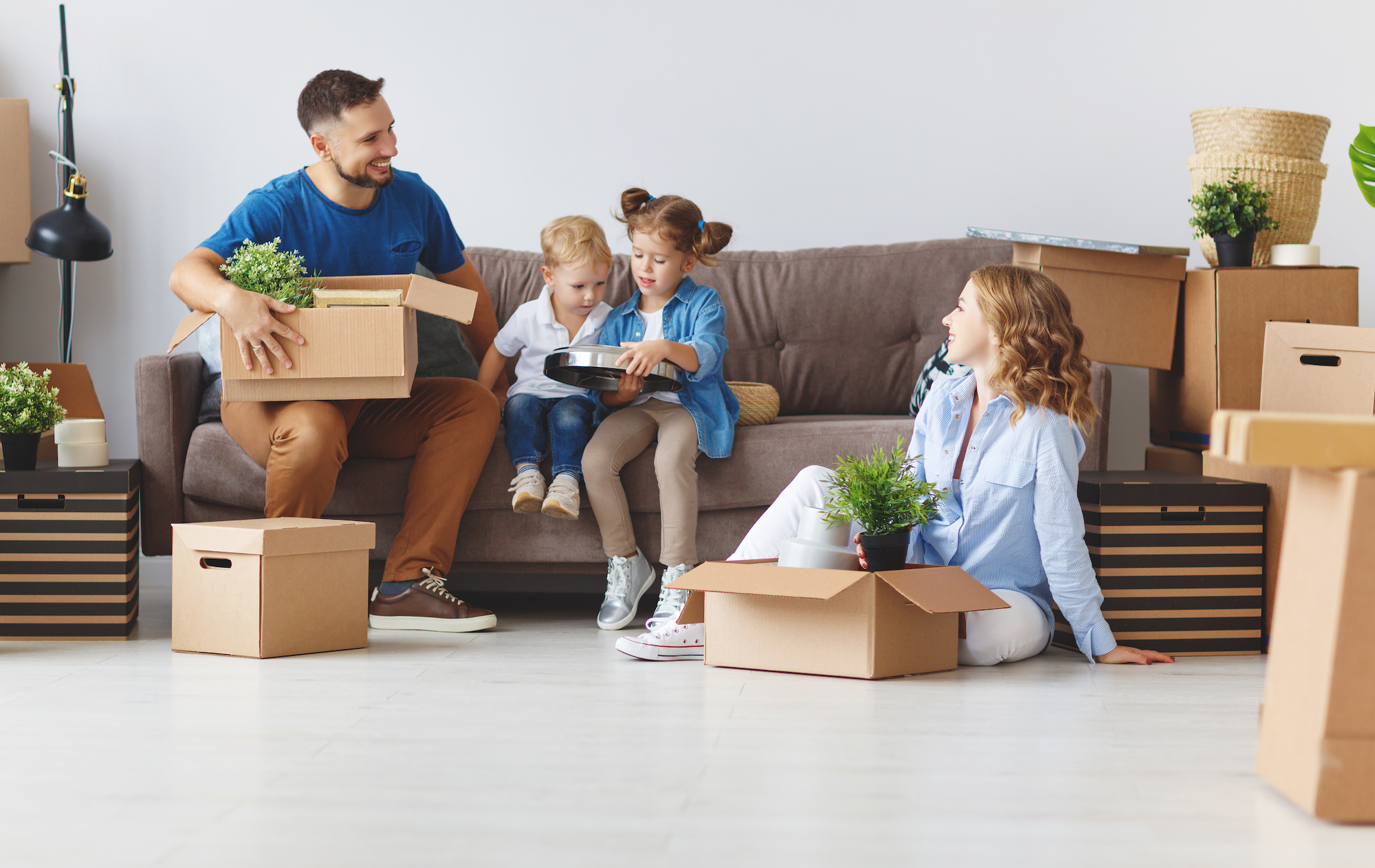 happy family mother father and children move to new apartment and unpack boxes